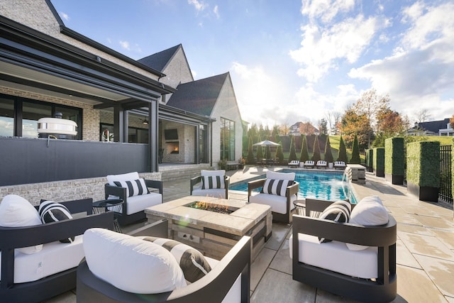 view of patio featuring pool water feature, a fenced in pool, and an outdoor living space with a fire pit