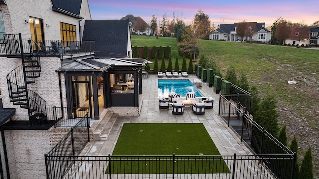 pool at dusk with a patio and an outdoor hangout area