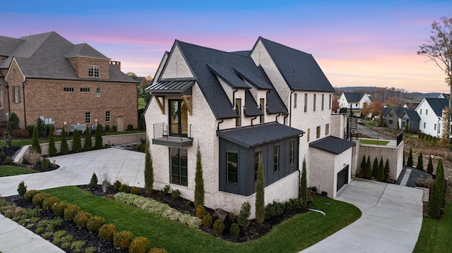 property exterior at dusk featuring a lawn, a balcony, and a garage