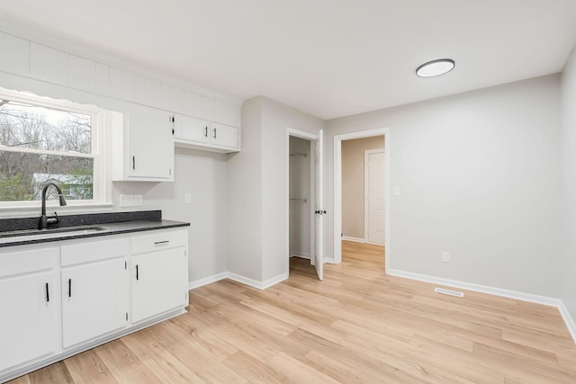 kitchen with white cabinetry, sink, and light hardwood / wood-style flooring