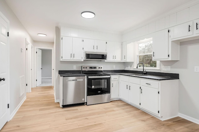 kitchen with sink, white cabinets, light hardwood / wood-style floors, and appliances with stainless steel finishes