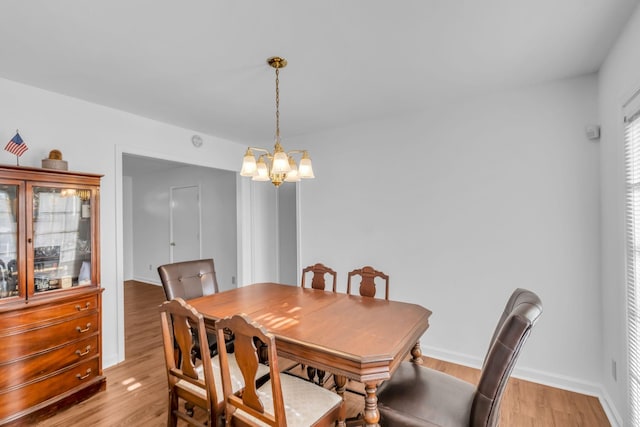 dining area with light hardwood / wood-style flooring and a notable chandelier