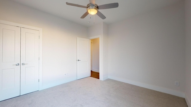 unfurnished bedroom with a closet, light colored carpet, and ceiling fan