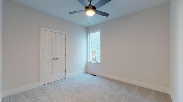 unfurnished bedroom featuring a closet, light colored carpet, and ceiling fan