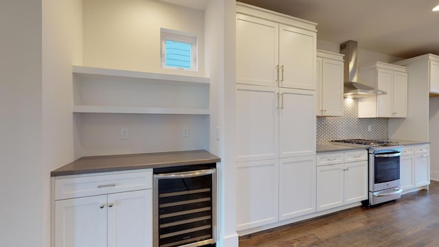 kitchen with white cabinets, wall chimney exhaust hood, stainless steel range, dark hardwood / wood-style flooring, and beverage cooler