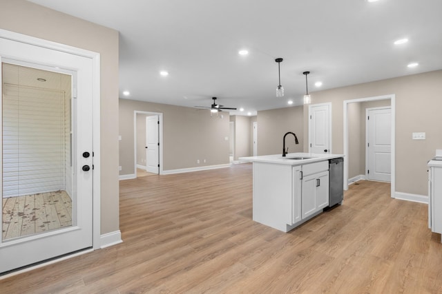 kitchen featuring white cabinetry, sink, light hardwood / wood-style flooring, pendant lighting, and a center island with sink