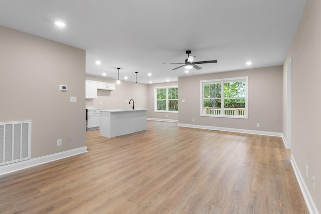 unfurnished living room with light hardwood / wood-style floors, ceiling fan, and sink