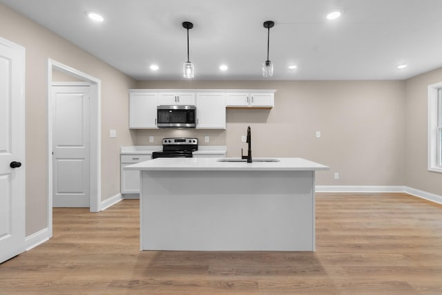 kitchen featuring white cabinetry, sink, hanging light fixtures, stainless steel appliances, and a kitchen island with sink