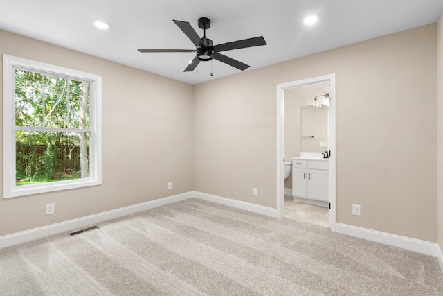 unfurnished bedroom with ceiling fan, light colored carpet, and ensuite bath