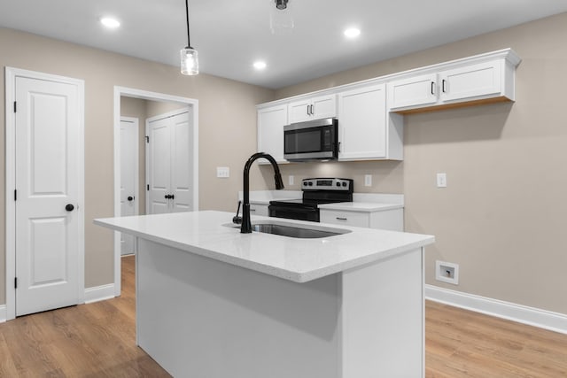 kitchen with appliances with stainless steel finishes, decorative light fixtures, light hardwood / wood-style flooring, white cabinets, and an island with sink