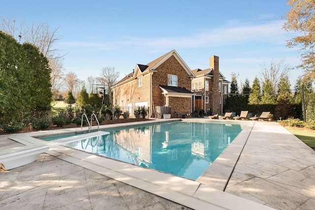 view of swimming pool with a diving board and a patio