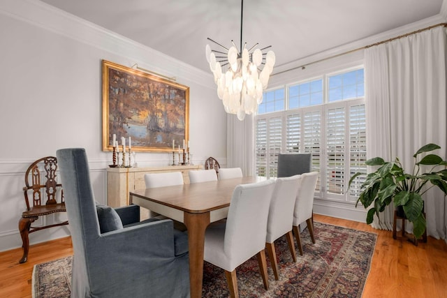 dining room featuring ornamental molding, light wood-type flooring, a notable chandelier, and a healthy amount of sunlight