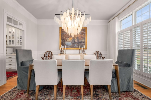 dining space with hardwood / wood-style flooring, a notable chandelier, and crown molding