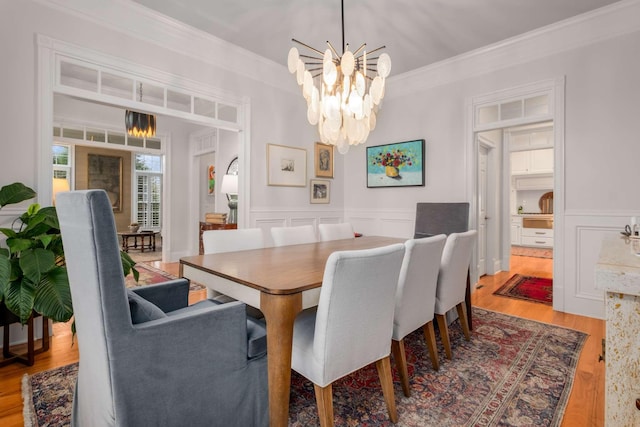 dining area featuring crown molding, wood-type flooring, and a notable chandelier