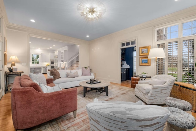 living room with a chandelier, crown molding, light hardwood / wood-style flooring, and a healthy amount of sunlight