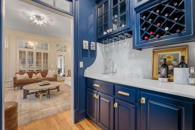 bar featuring blue cabinetry, sink, and light wood-type flooring