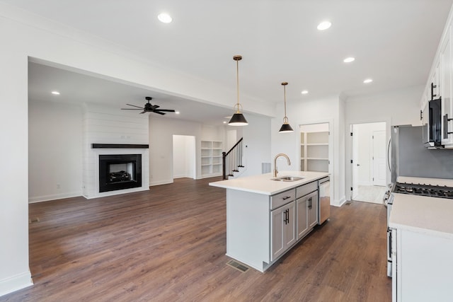 kitchen featuring stainless steel appliances, pendant lighting, dark hardwood / wood-style floors, white cabinetry, and an island with sink