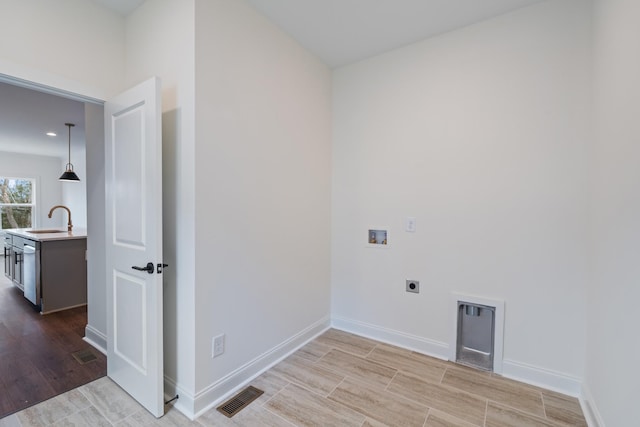 clothes washing area with electric dryer hookup, light hardwood / wood-style floors, sink, and hookup for a washing machine