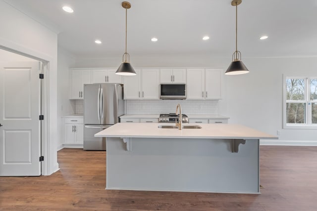 kitchen with hanging light fixtures, light hardwood / wood-style flooring, white cabinets, and stainless steel appliances