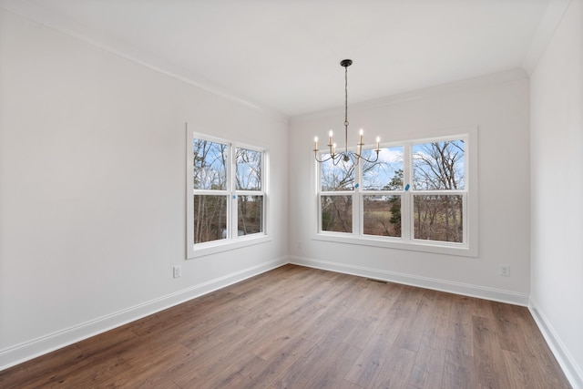 unfurnished dining area featuring a chandelier, crown molding, a healthy amount of sunlight, and hardwood / wood-style flooring