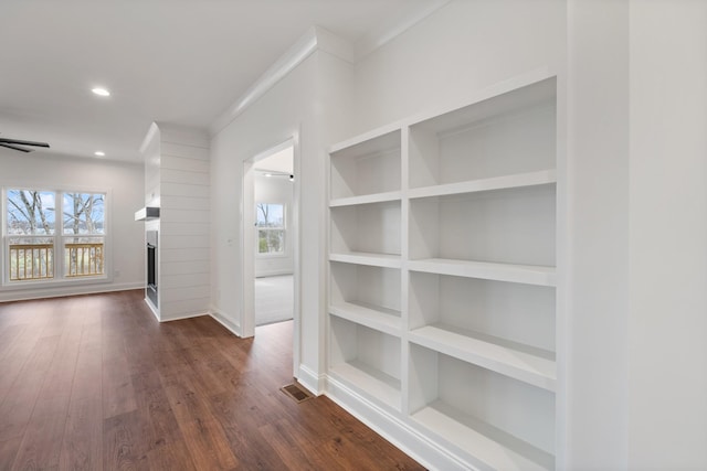 corridor featuring dark hardwood / wood-style floors, built in features, and ornamental molding