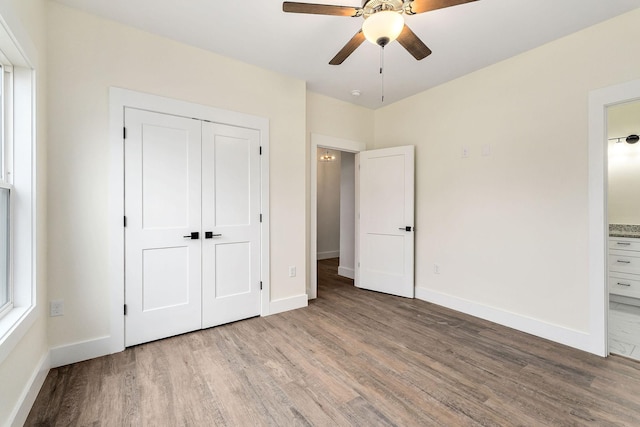 unfurnished bedroom featuring ceiling fan, light wood-type flooring, connected bathroom, and a closet