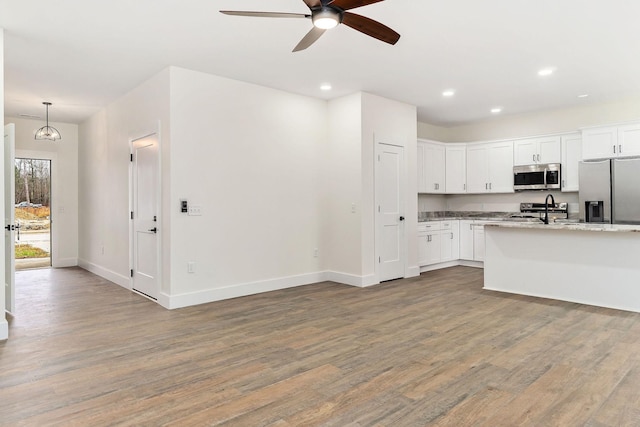 kitchen featuring white cabinetry, light stone counters, hardwood / wood-style flooring, and appliances with stainless steel finishes