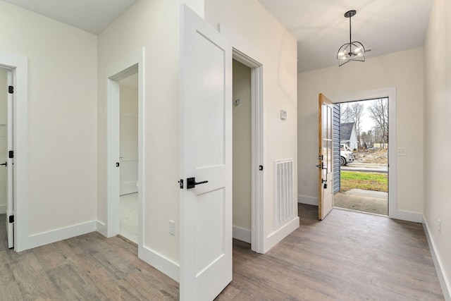 entrance foyer with light hardwood / wood-style flooring and a notable chandelier