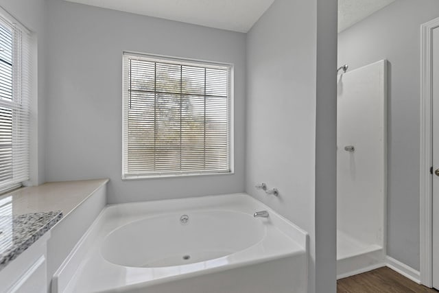 bathroom with plus walk in shower, wood-type flooring, a textured ceiling, and plenty of natural light