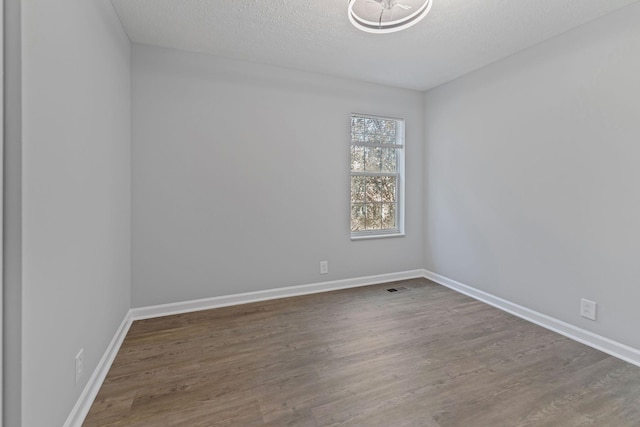 unfurnished room with dark hardwood / wood-style flooring and a textured ceiling