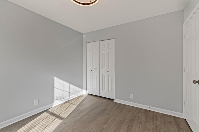 unfurnished bedroom featuring a closet and dark wood-type flooring