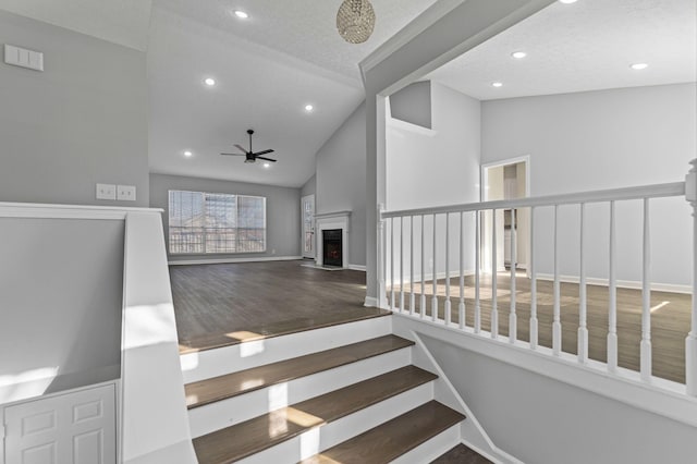 staircase featuring hardwood / wood-style floors, ceiling fan, a textured ceiling, and high vaulted ceiling