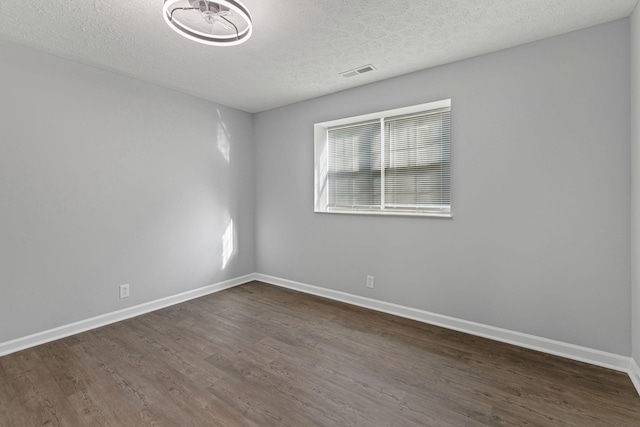 empty room featuring a textured ceiling and dark hardwood / wood-style floors