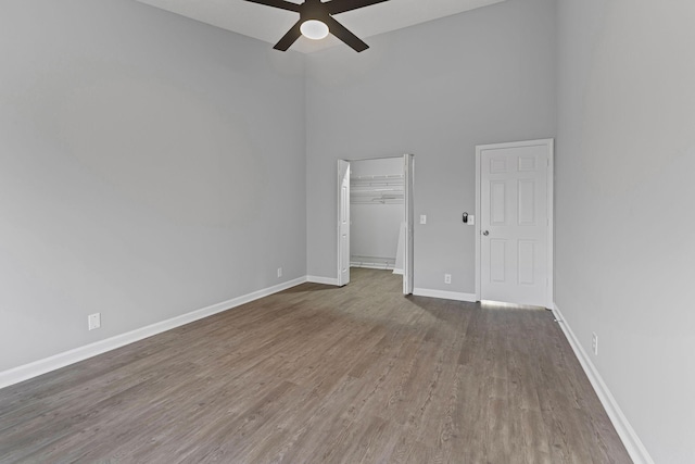 unfurnished bedroom featuring ceiling fan, a towering ceiling, and dark hardwood / wood-style floors