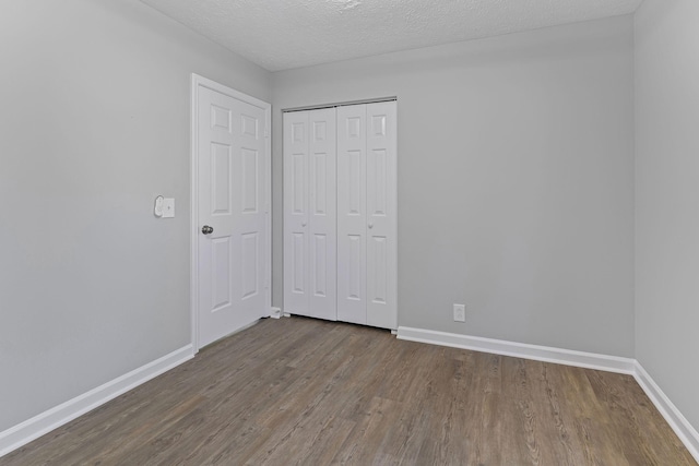 unfurnished bedroom featuring hardwood / wood-style floors, a textured ceiling, and a closet