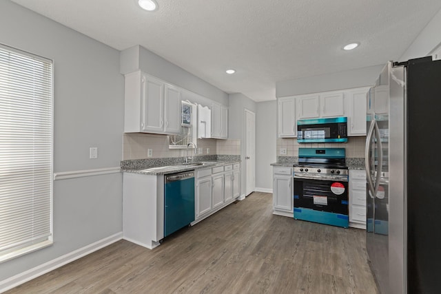 kitchen with appliances with stainless steel finishes, a textured ceiling, white cabinetry, and dark wood-type flooring