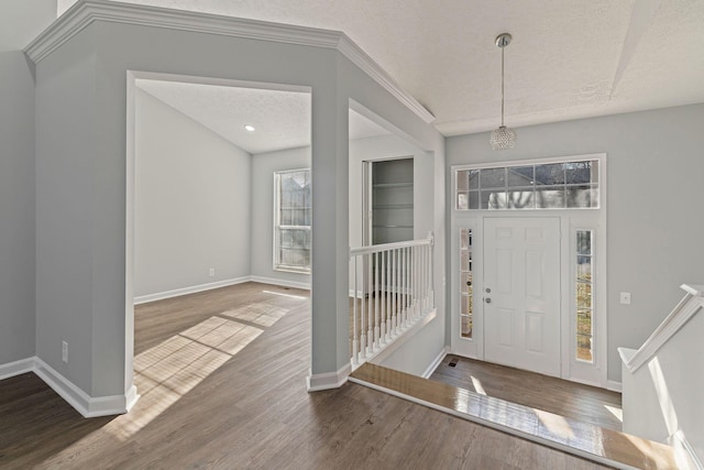 foyer featuring crown molding, a textured ceiling, a wealth of natural light, and dark wood-type flooring