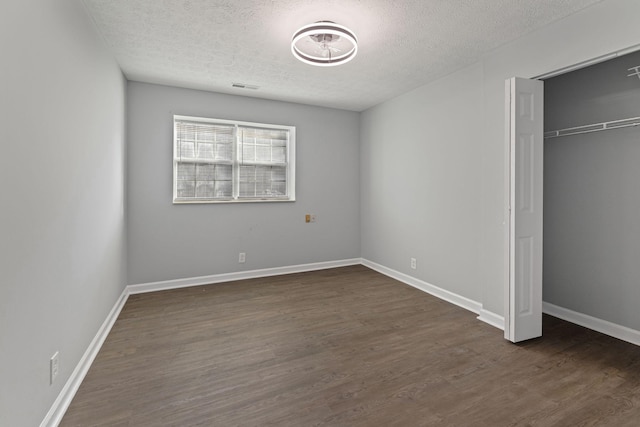 unfurnished bedroom featuring a textured ceiling, a closet, and dark hardwood / wood-style floors