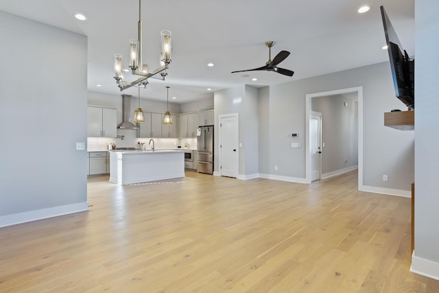 unfurnished living room featuring ceiling fan, sink, and light wood-type flooring