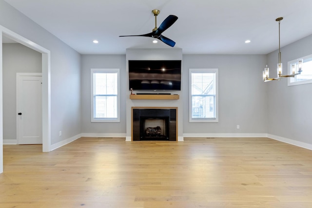 unfurnished living room with light hardwood / wood-style flooring and ceiling fan with notable chandelier