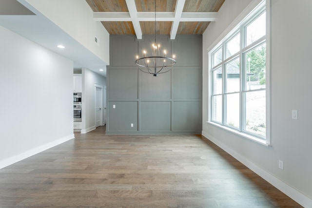 unfurnished dining area with plenty of natural light, coffered ceiling, light hardwood / wood-style floors, and a notable chandelier