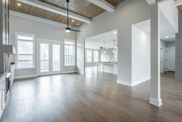 unfurnished living room with dark hardwood / wood-style flooring, beam ceiling, french doors, and ceiling fan