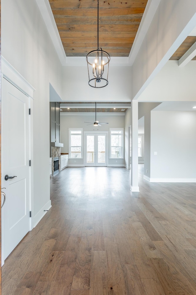 interior space featuring dark wood-type flooring, french doors, wooden ceiling, a notable chandelier, and a towering ceiling