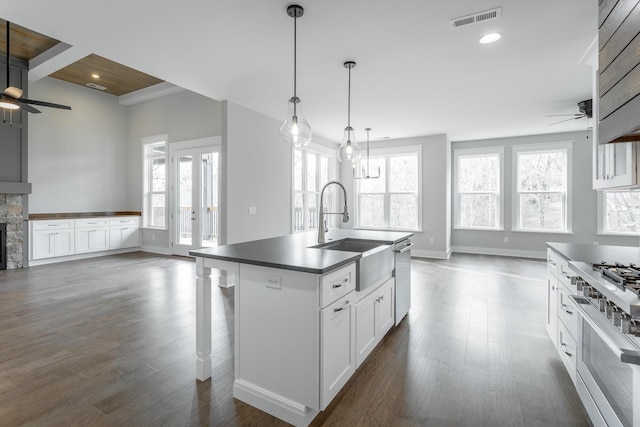 kitchen featuring sink, ceiling fan, white cabinetry, a center island with sink, and decorative light fixtures