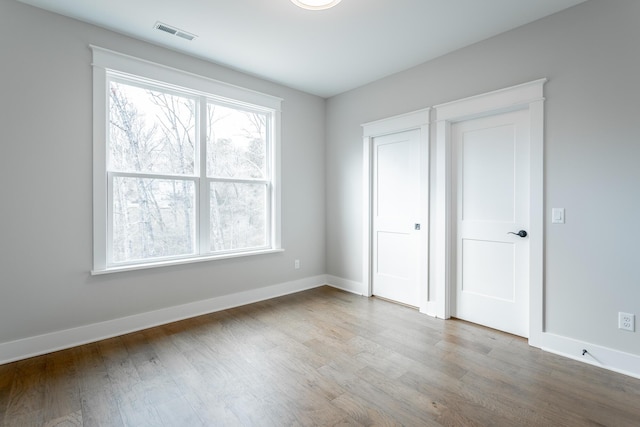 unfurnished bedroom featuring wood-type flooring and multiple windows