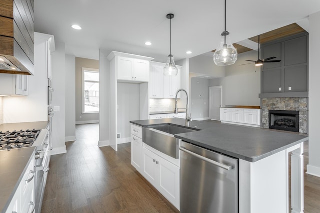 kitchen featuring appliances with stainless steel finishes, white cabinetry, an island with sink, sink, and dark wood-type flooring