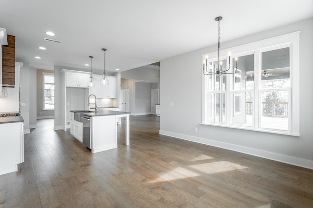 kitchen with a breakfast bar area, dishwasher, white cabinetry, hanging light fixtures, and a kitchen island with sink