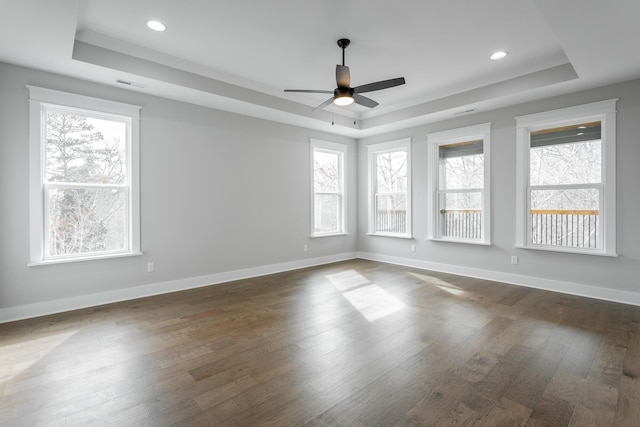 spare room with dark wood-type flooring, ceiling fan, and a tray ceiling