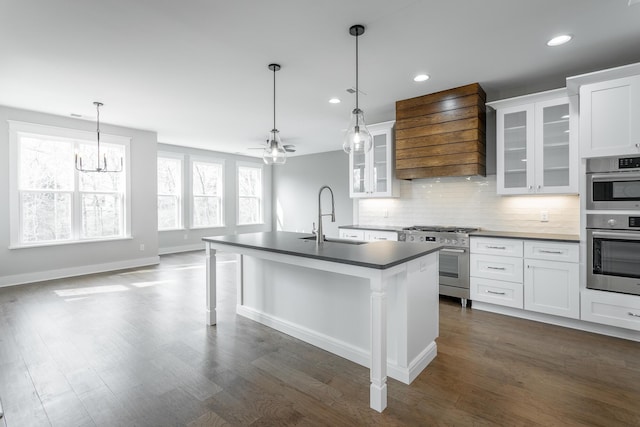 kitchen featuring appliances with stainless steel finishes, an island with sink, white cabinets, a kitchen bar, and custom range hood