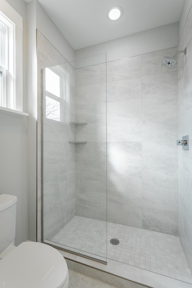 bathroom with tiled shower and toilet